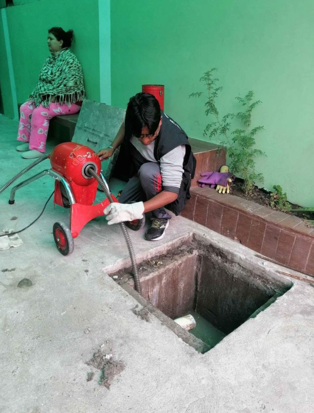 Técnico realizando limpieza en caja de inspección